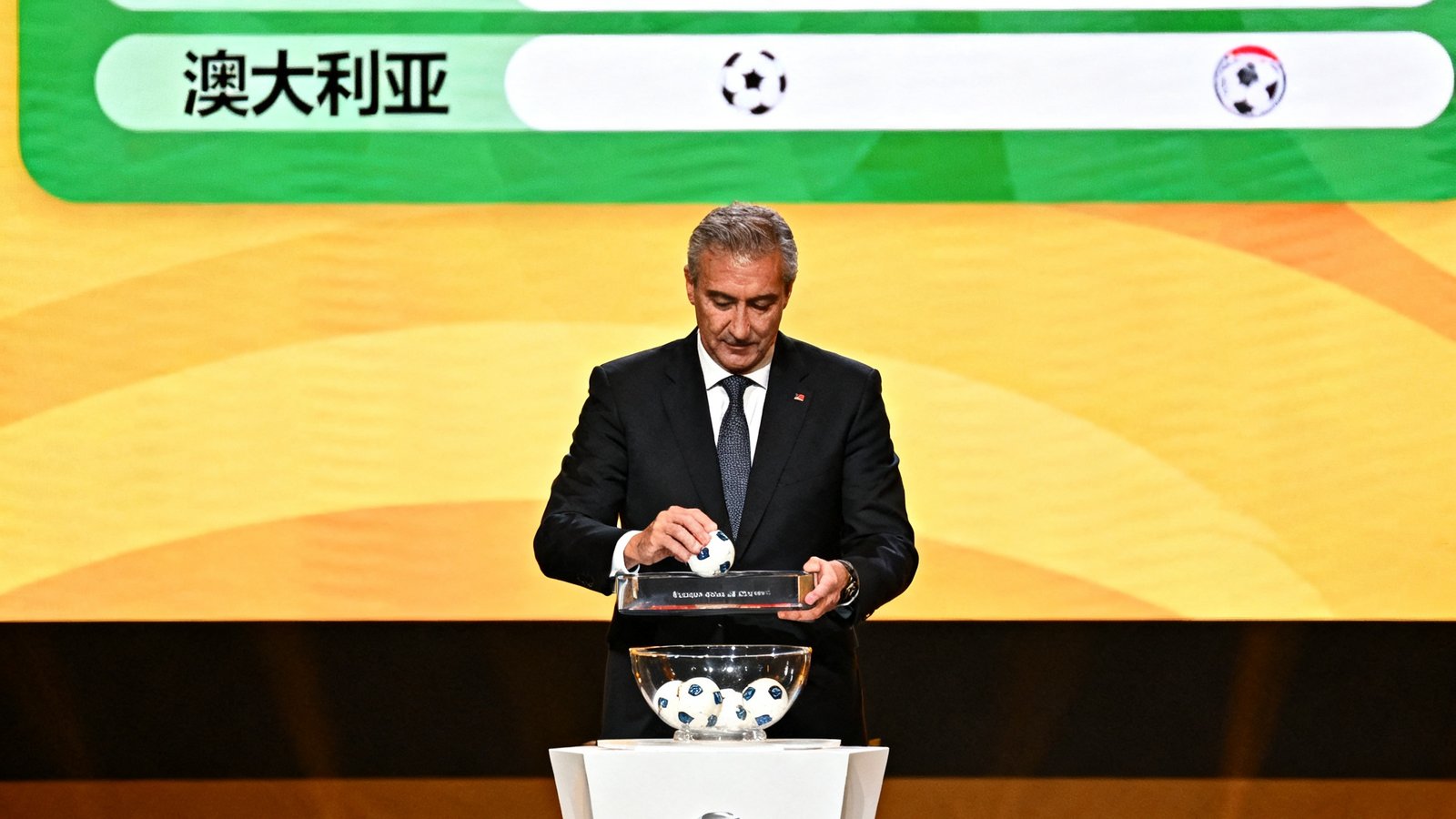 2026世界杯预选赛抽签仪式现场，国际足联官员在台上抽取球队分组球，大屏幕展示分组结果